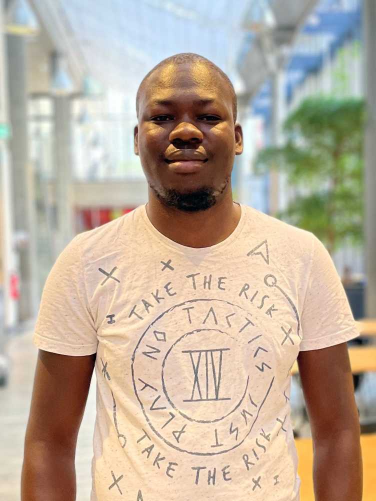 Frank stands in front of a blurred background at ETH and wears a white t-shirt
