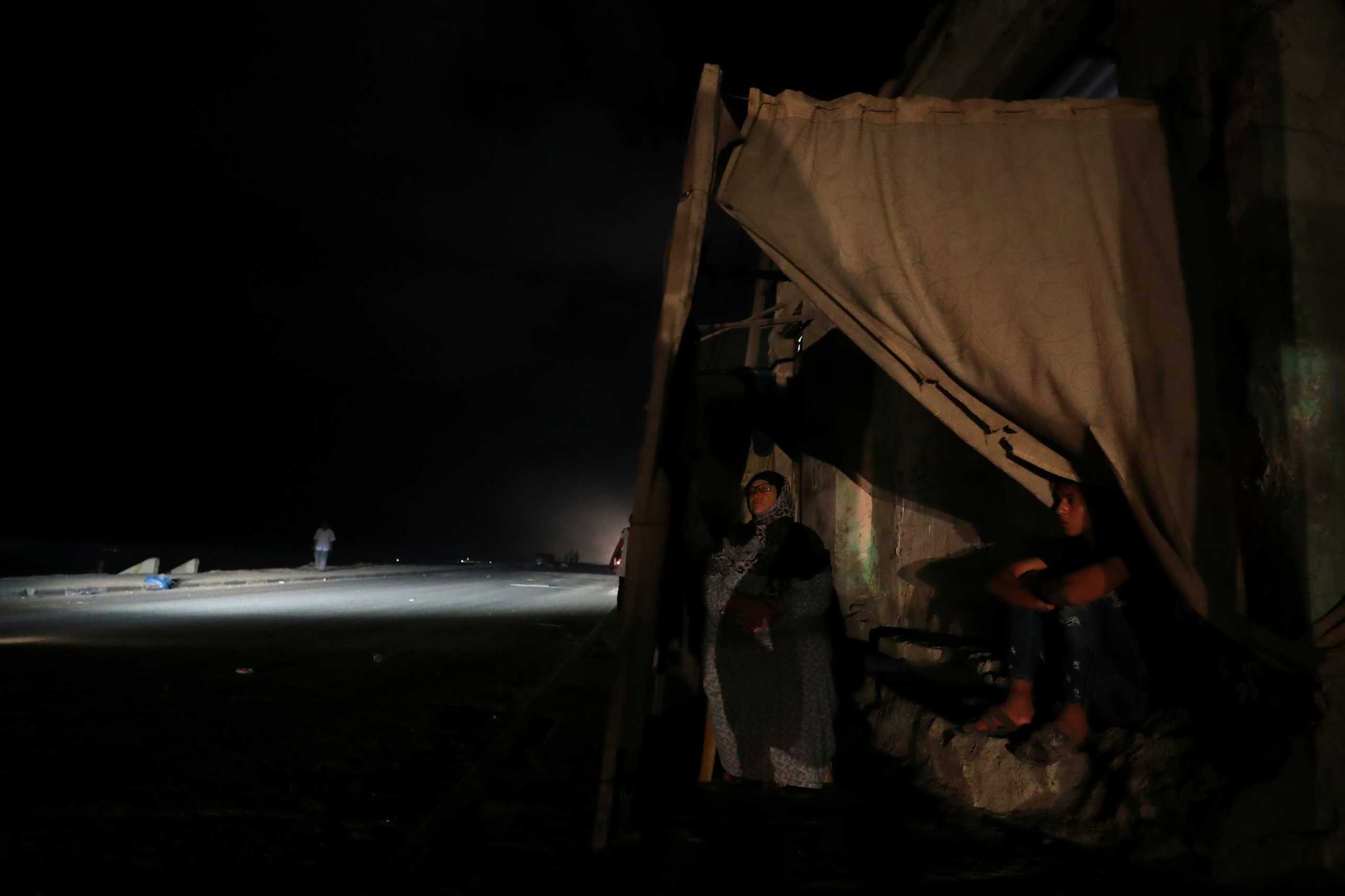 Two people sit in a tent amidst a dark backdrop