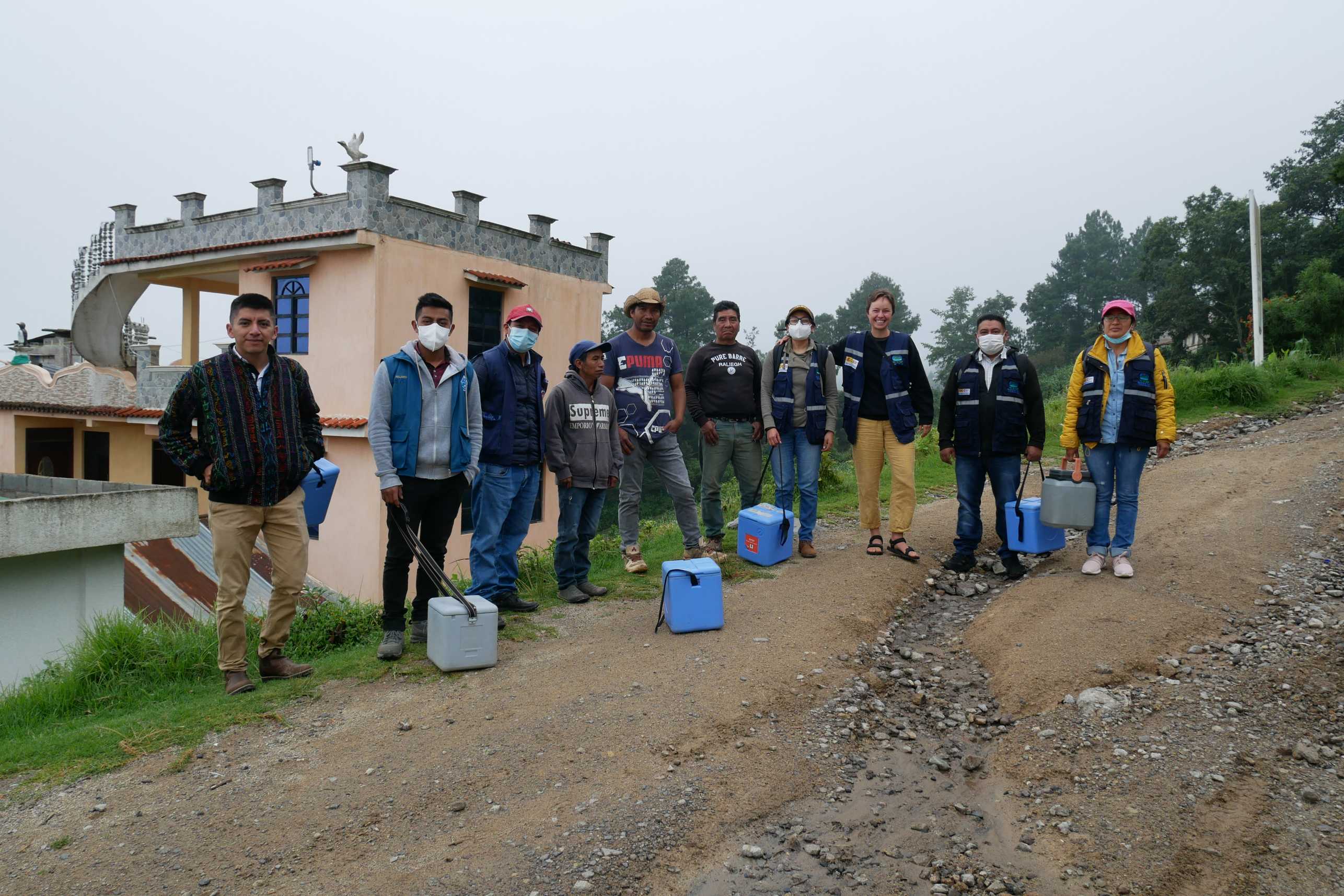 A group of researchers stands on the road facing the camera